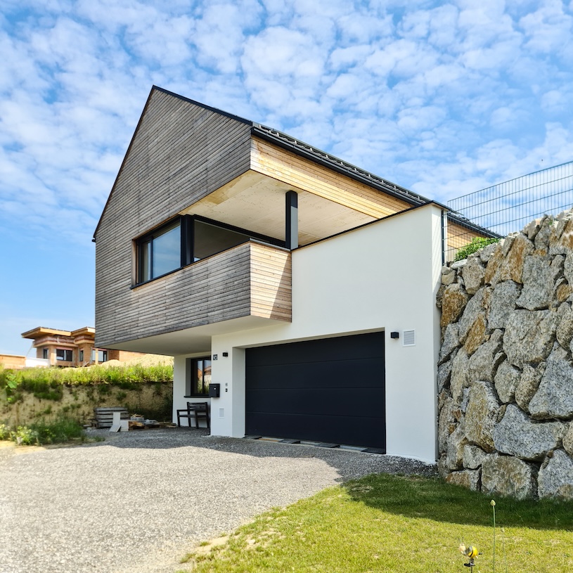 Garage und Eingang bei Haus in Hanglage mit seitlicher Stützmauer.