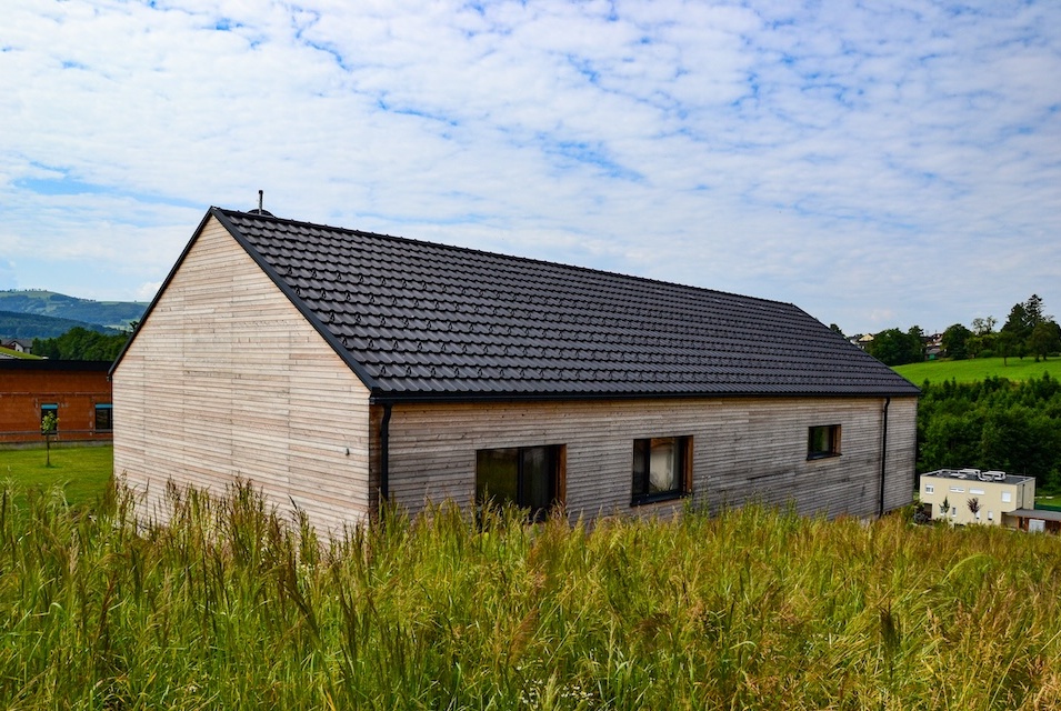 Blick von oben auf Haus in Hanglage mit Holzfassade.