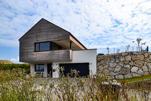 Garage und Eingang bei Haus in Hanglage mit seitlicher Stützmauer.