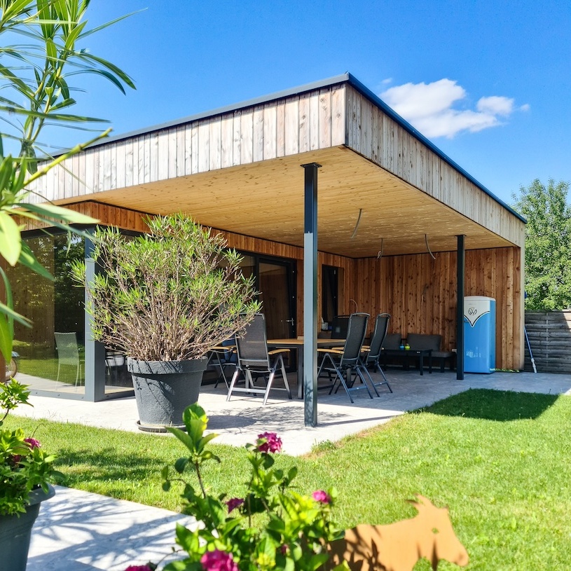 Das Poolhaus mit Überdachung macht Schatten auf die darunter stehende Sitzgarnitur.