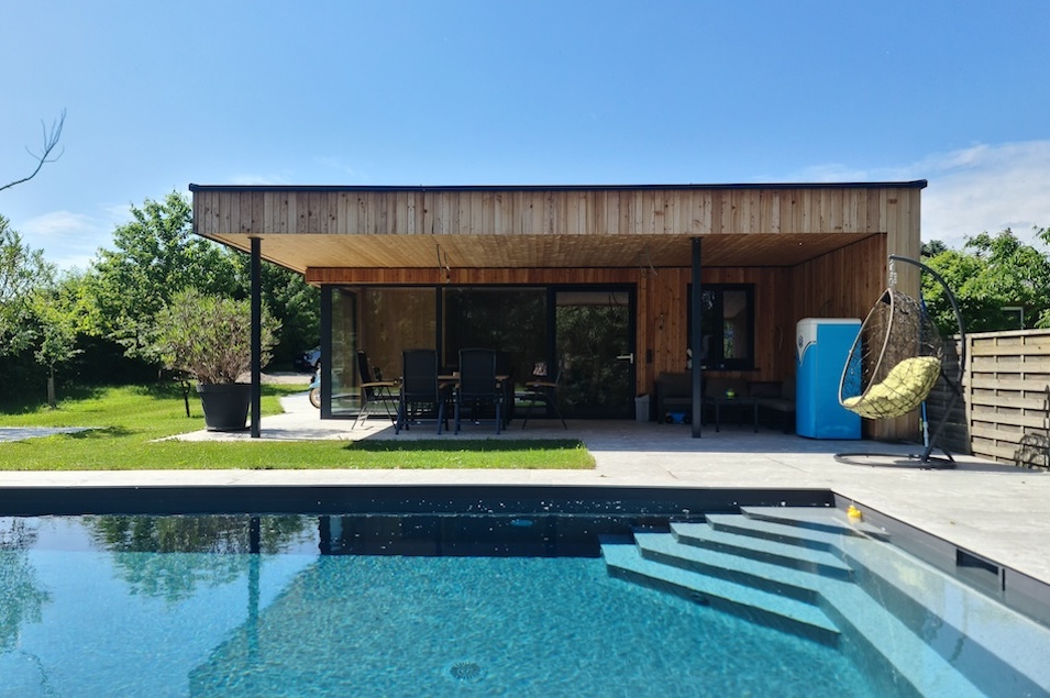 Das Poolhaus in Holzbauweise hinter dem Schwimmbecken.